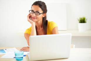 Cheerful hispanic worker with glasses using her computer in the office