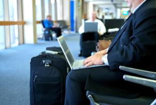 An image of a business man on his laptop in the airport while waiting for his flight