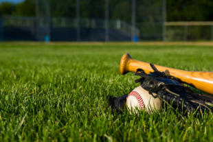 a baseball, glove and bat on a baseball diamond.