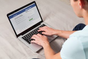 MALAGA, SPAIN - NOVEMBER 10, 2015: Facebook login page in a laptop computer screen. Man typing on the keyboard. Facebook is the most famous social website all over the world.