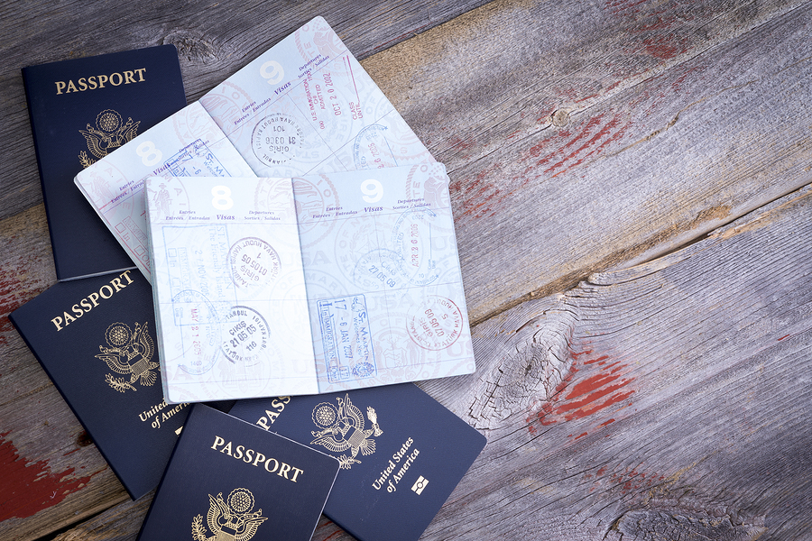 American passports lying on a rustic wooden table open to reveal hand stamps from customs officials on border control applied during traveling abroad